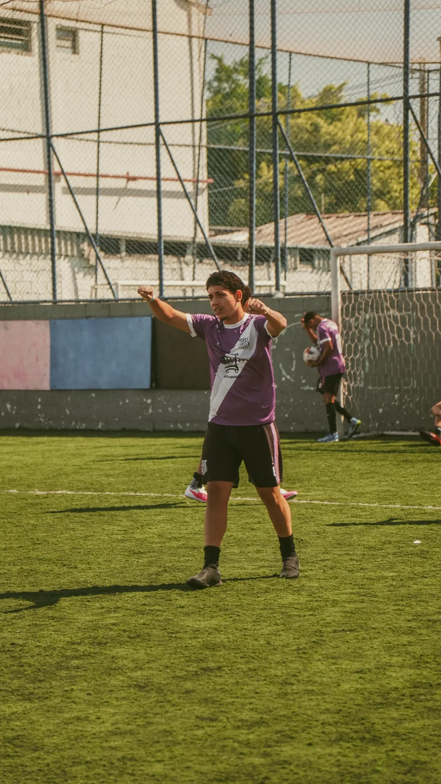 Jogador de uniforme roxo gesticula para outros participantes no campo